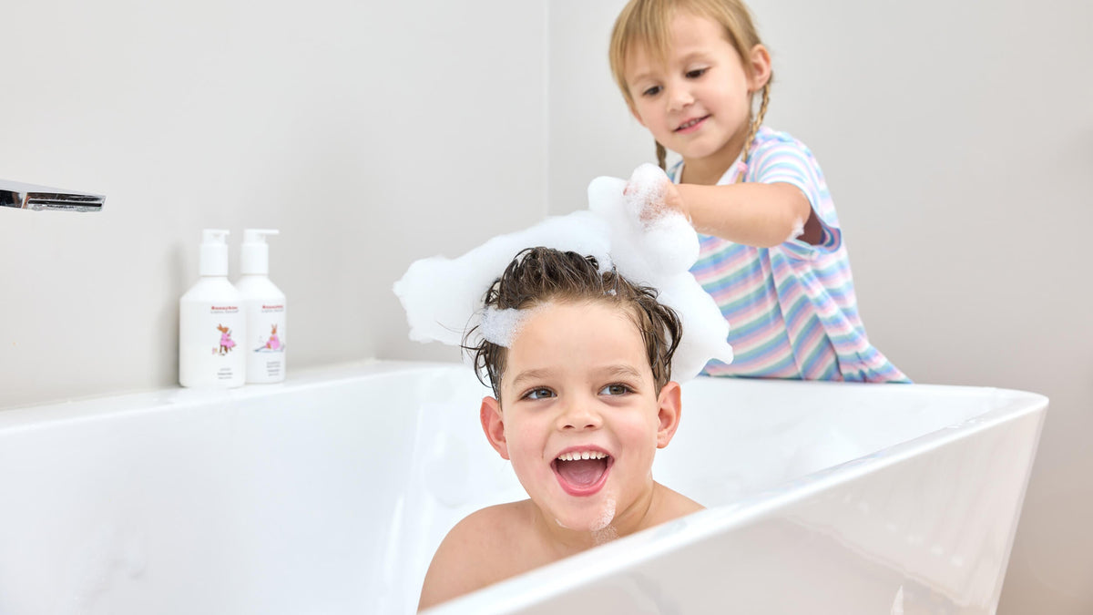 Children playing with bath foam beside white Bunnykins bodycare bottles