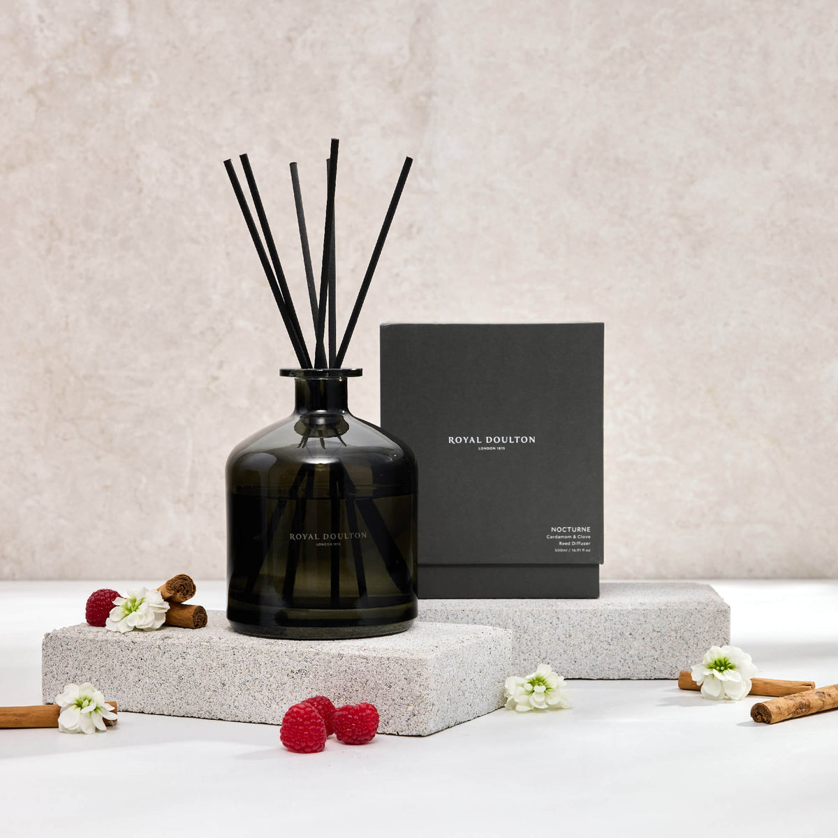 Royal Doulton Nocturne 500ml diffuser with black reeds in a dark glass bottle, beside its black box and raspberries.