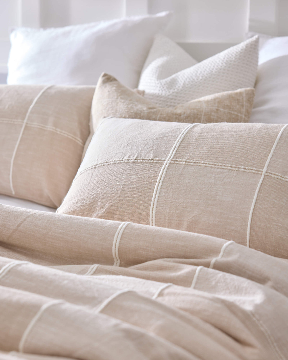 Royal Doulton Whitby beige grid duvet cover styled with matching cushions and white pillows