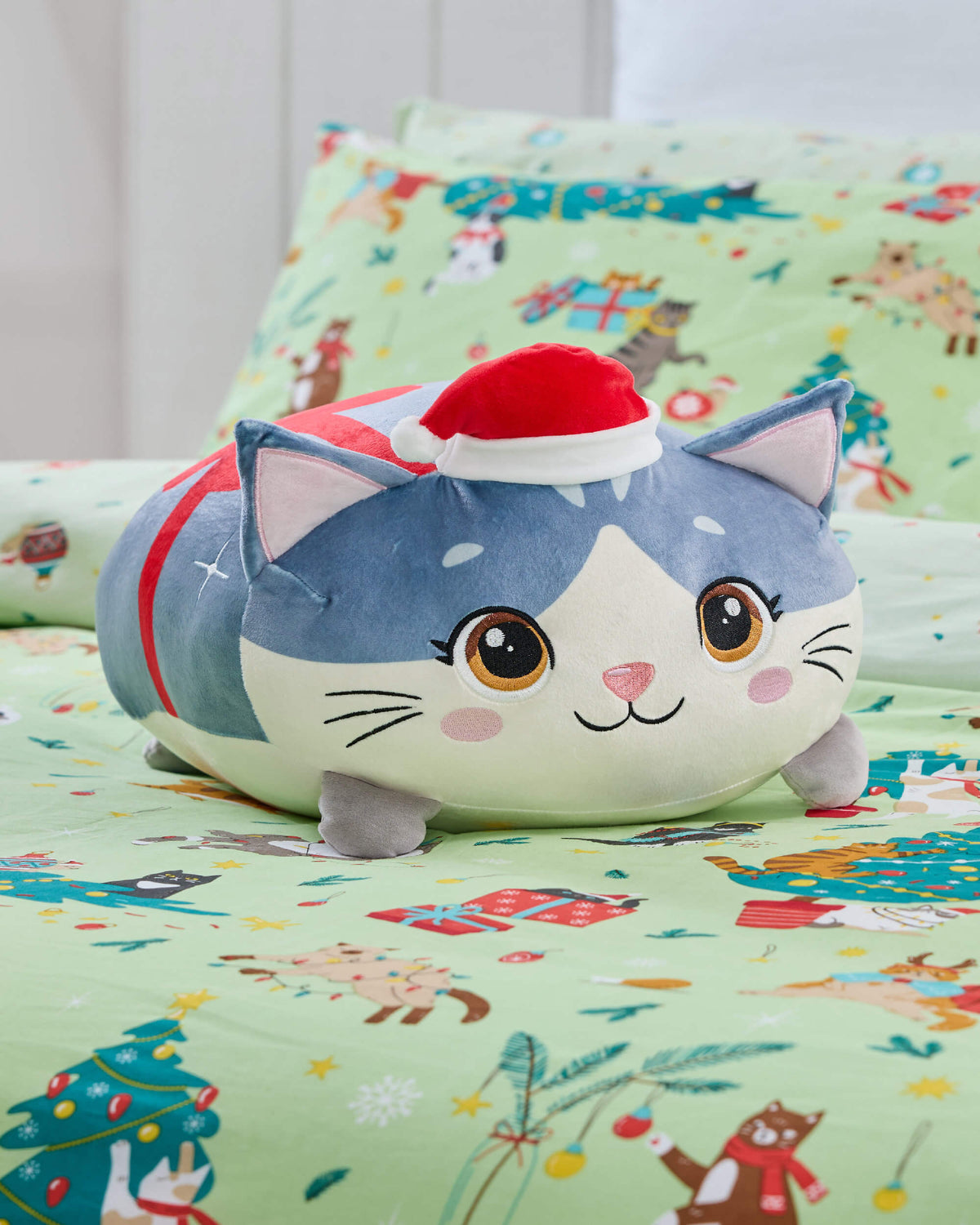 Round blue-and-white Twill & Co Christmas cat cushion wearing a Santa hat on mint festive bedding