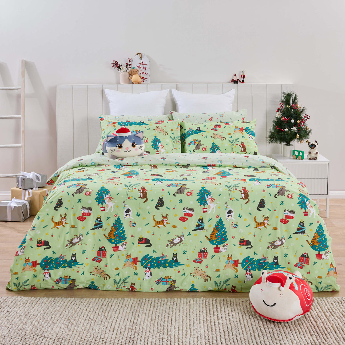 Full view of mint Twill & Co Cat-mas bedding with a blue cat cushion and red snail cushion nearby