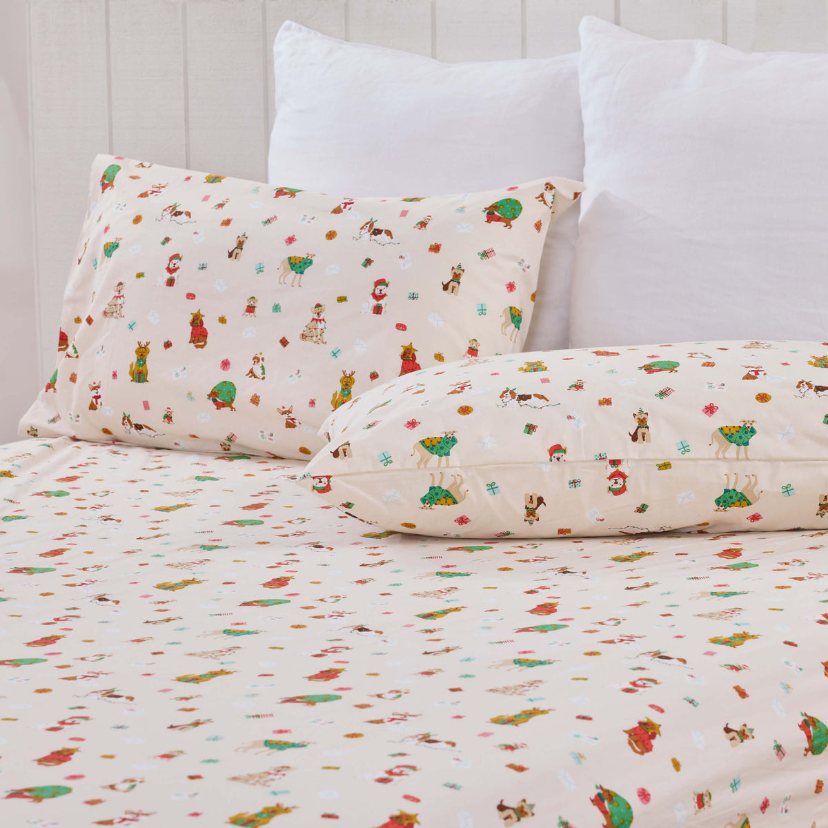 Close view of Twill & Co Santa Paws patterned pillows and sheets beneath plain white pillows
