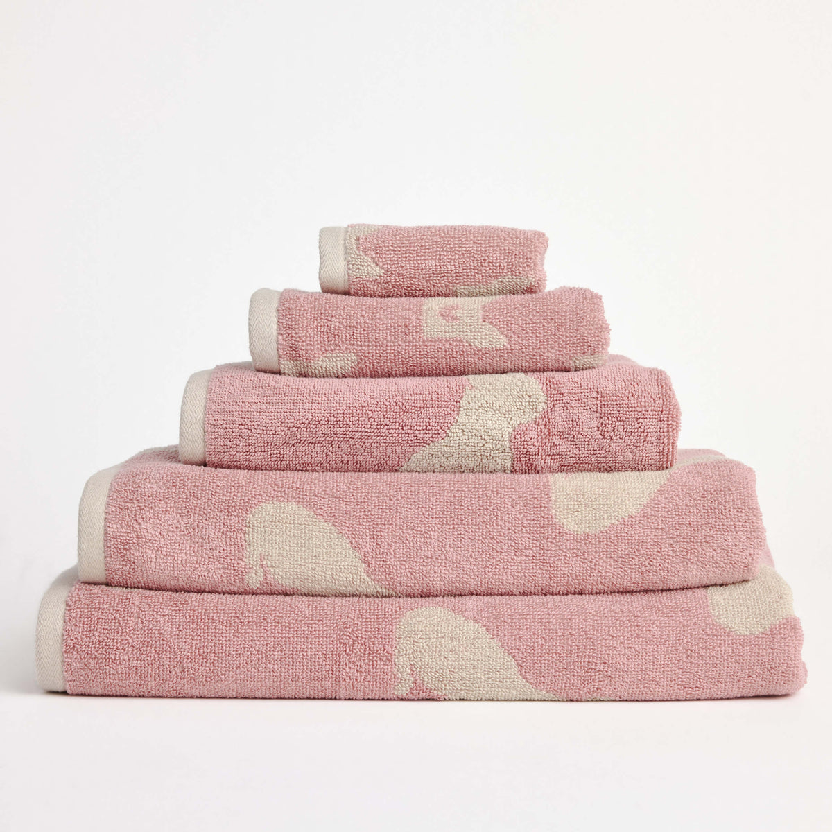 Stack of folded pink Twill & Co towels with cream dog silhouettes