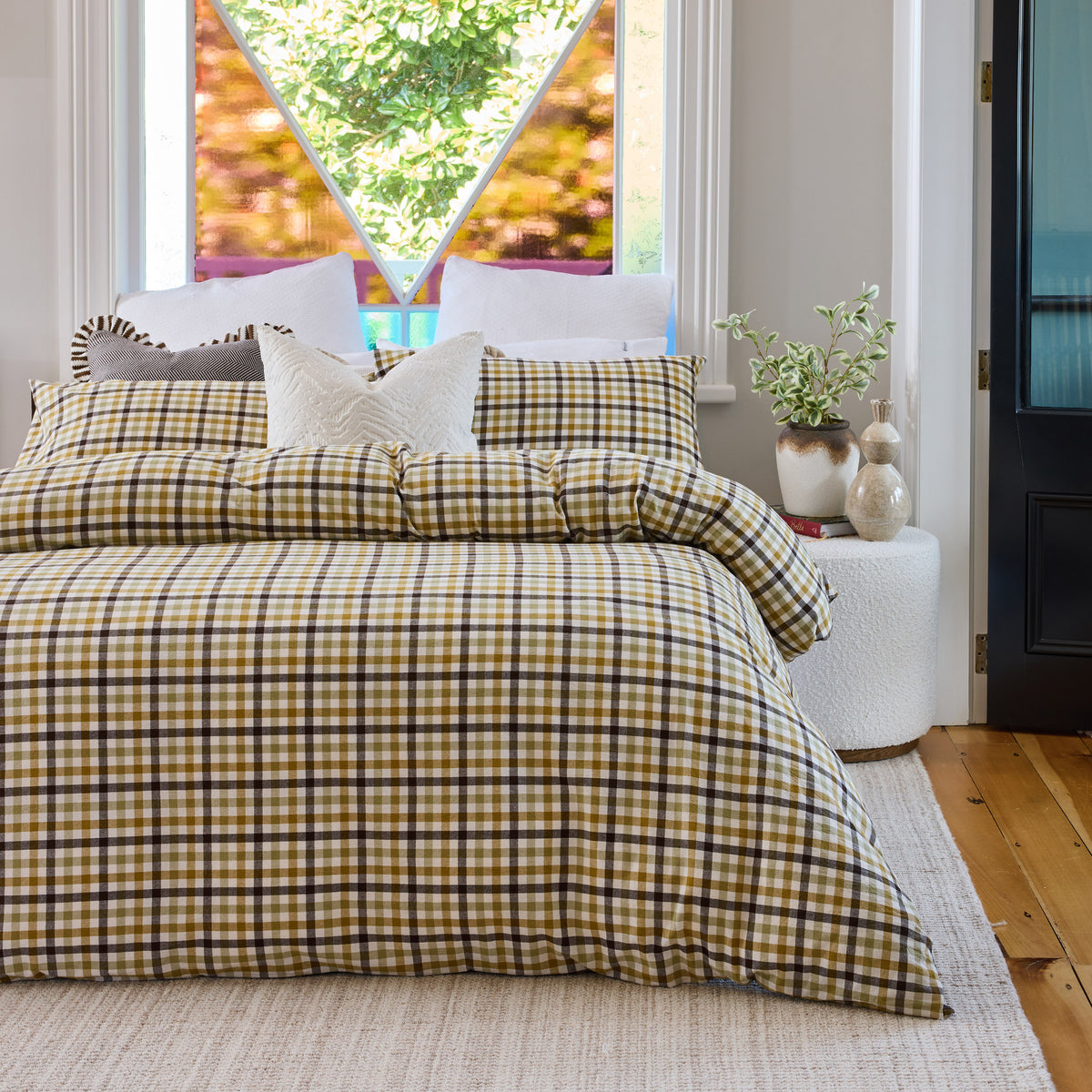 June & Jupiter Frankie checked duvet cover with neutral cushions beneath a window and hanging planter