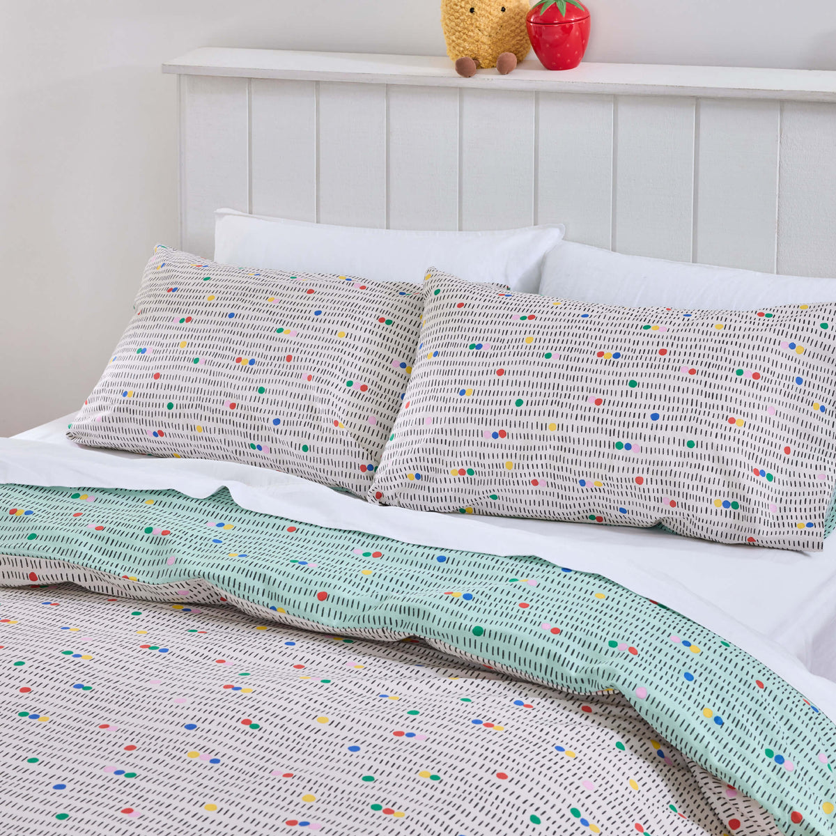 Twill & Co Fruit Loops bedding with tiny multicoloured motifs and a pale green reverse