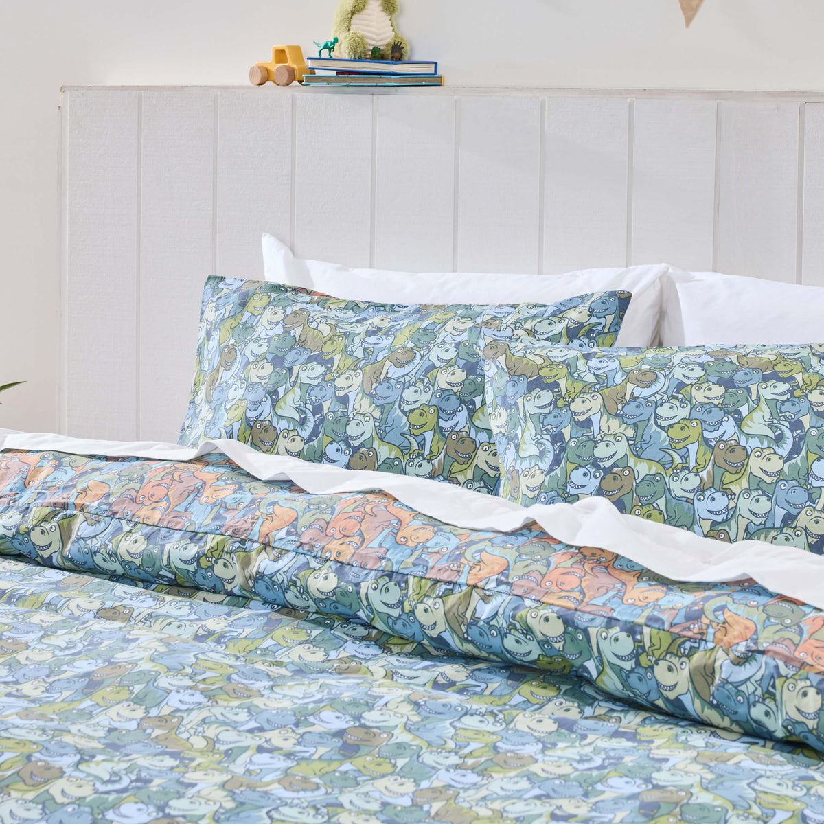 Blue and green cartoon dinosaurs on a Twill & Co kids duvet cover and matching pillowcases