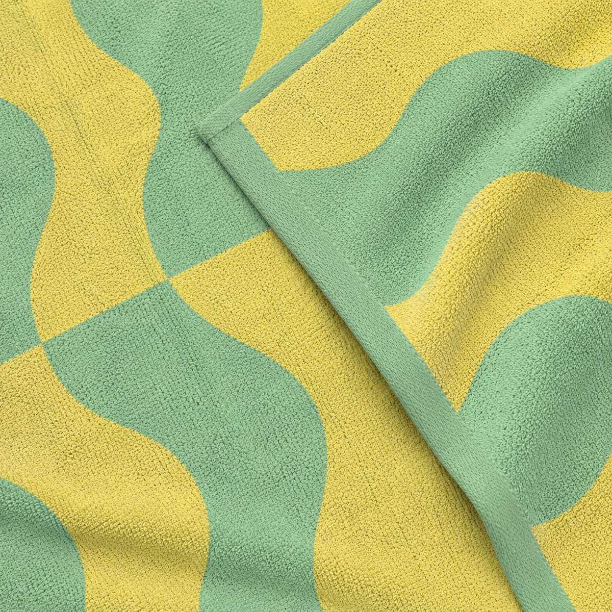 Close-up of yellow and green waves and a folded hem on the Twill & Co Squiggle beach towel