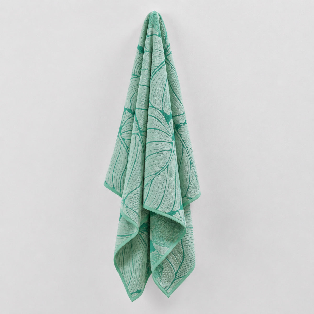 Green Twill & Co Tropical Time beach towel hanging with an outlined leaf pattern
