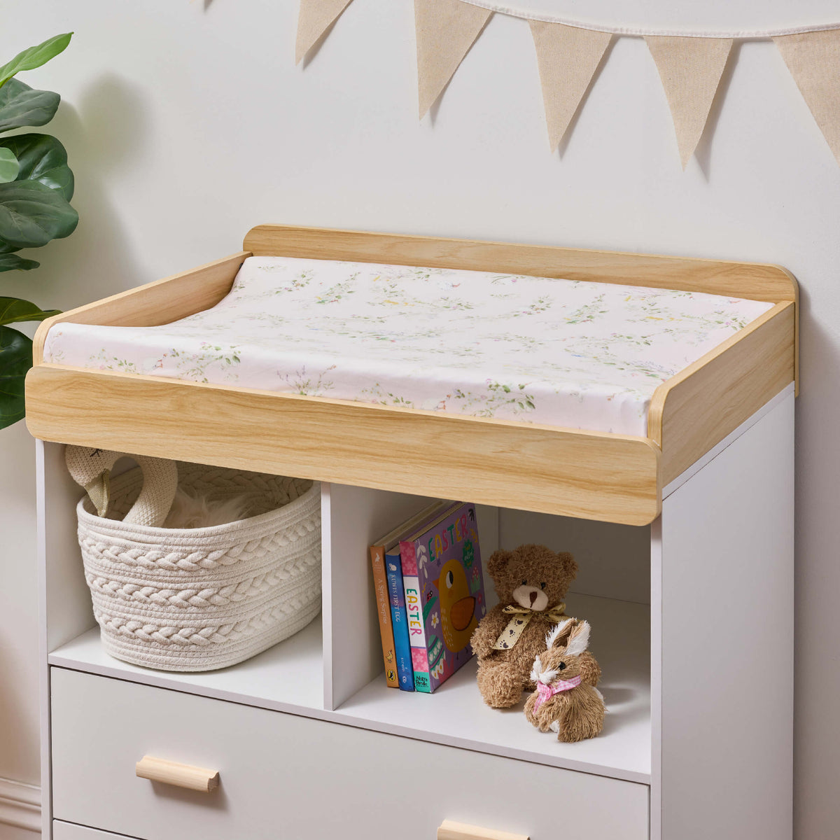 Pink floral Twill & Co change-pad cover on a wooden changing top above a nursery dresser