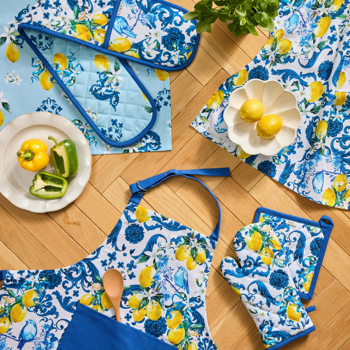 Blue and yellow Twill & Co kitchen textiles with lemon and floral patterns arranged around a wooden spoon
