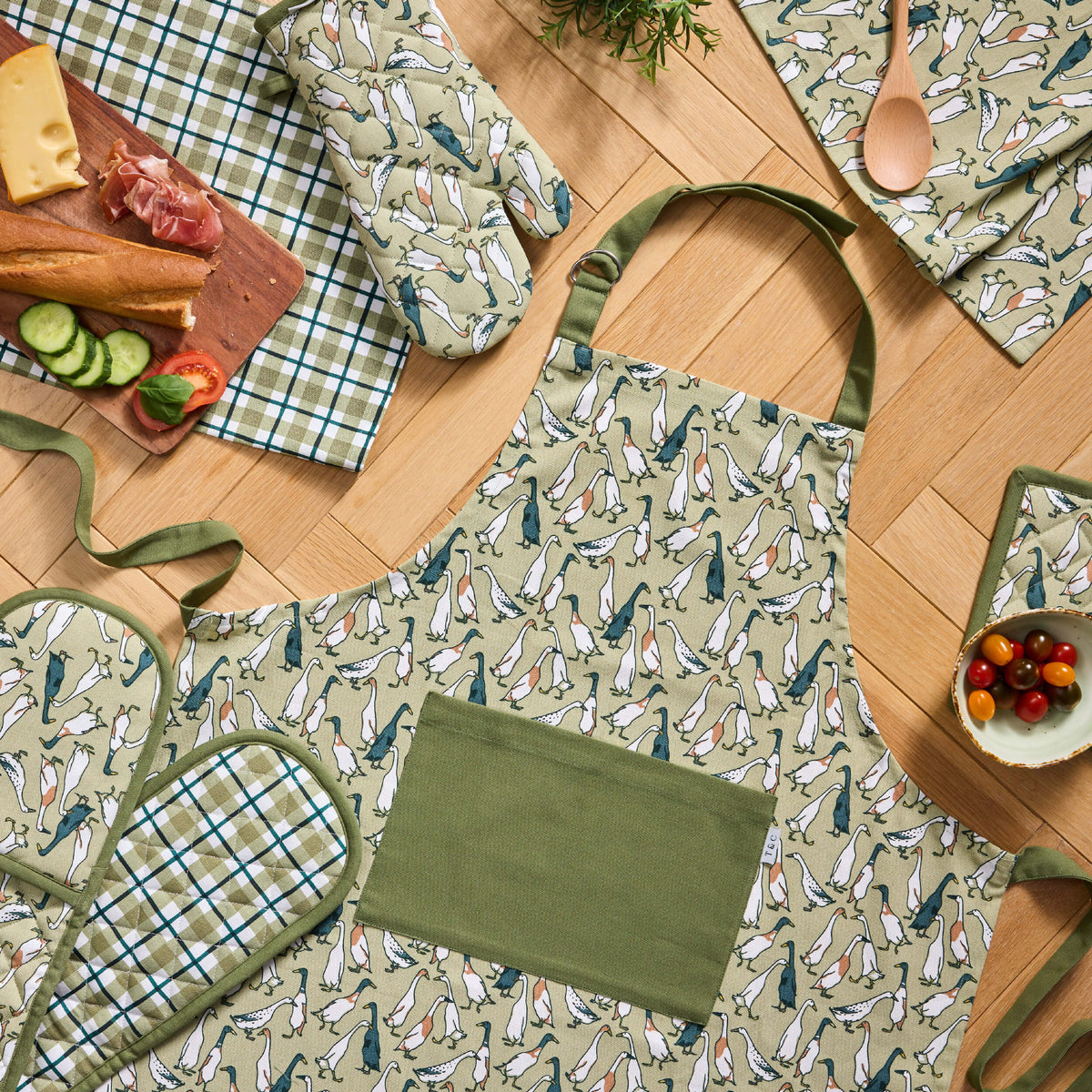 Twill & Co Duck Waddle apron with an olive pocket beside duck-print and checked kitchen textiles