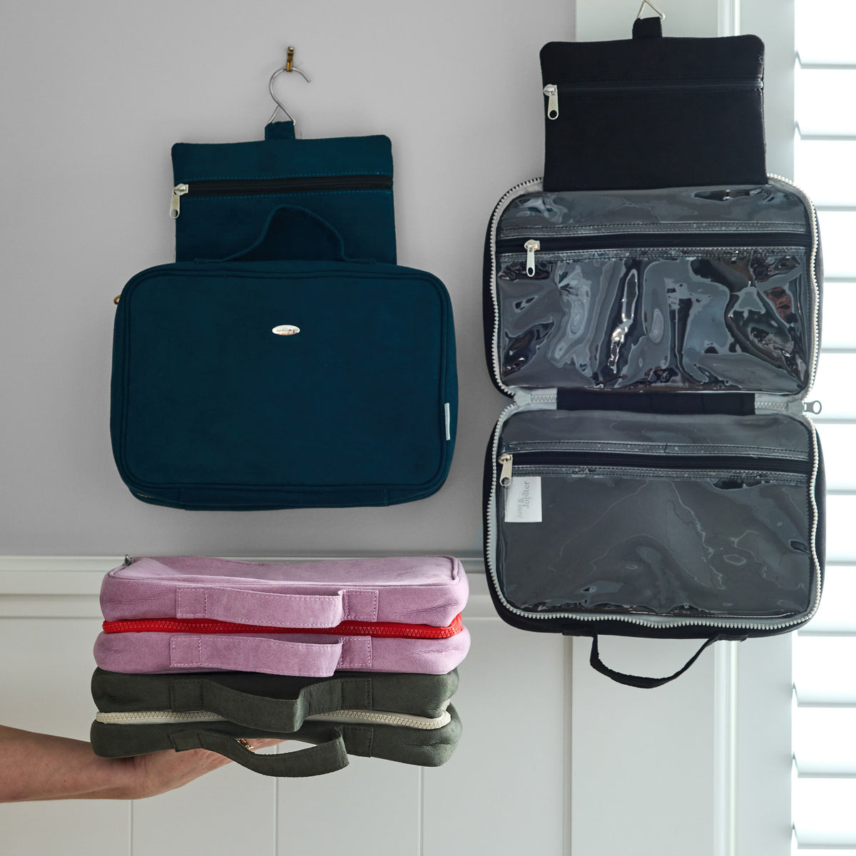 June & Jupiter hanging washbags displayed open and closed above a hand holding folded bags