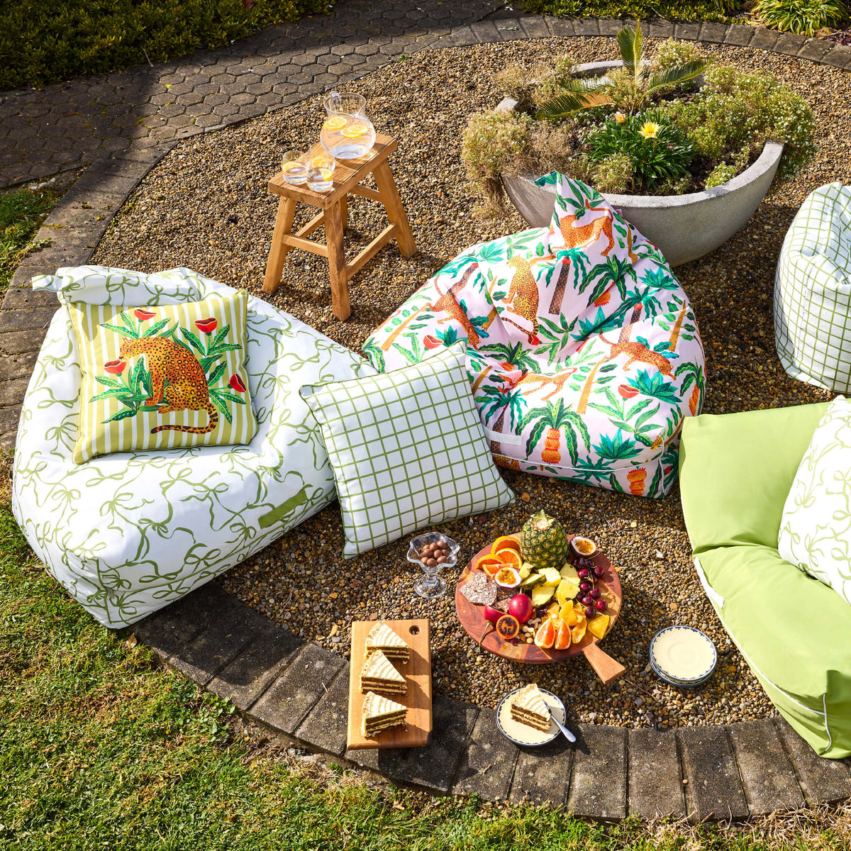 Twill & Co Tigerlily outdoor bean bags and cushions in green bow, check and colourful leopard prints on a garden patio.