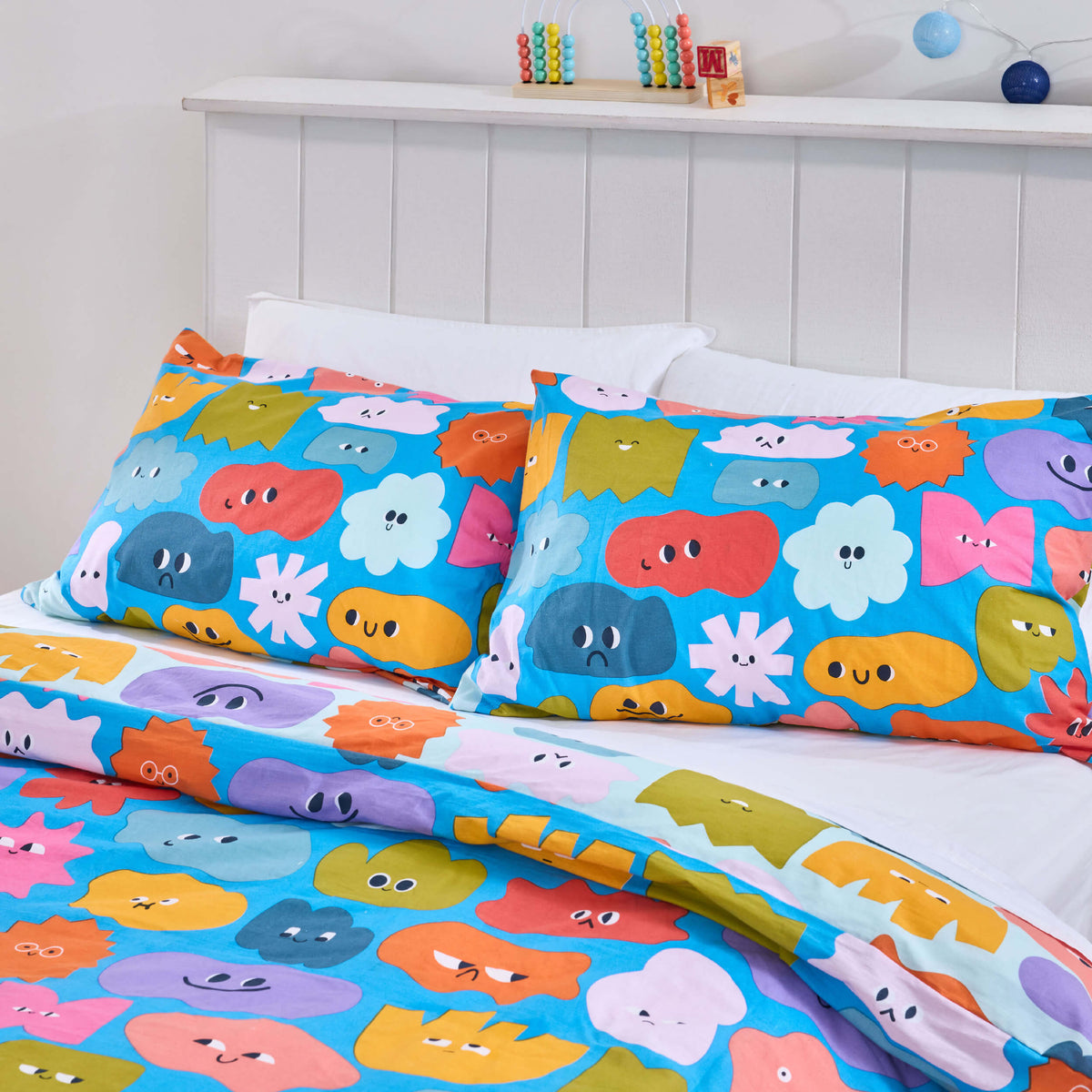 Twill & Co Big Feelings duvet cover with colourful smiling shapes on a bright blue background