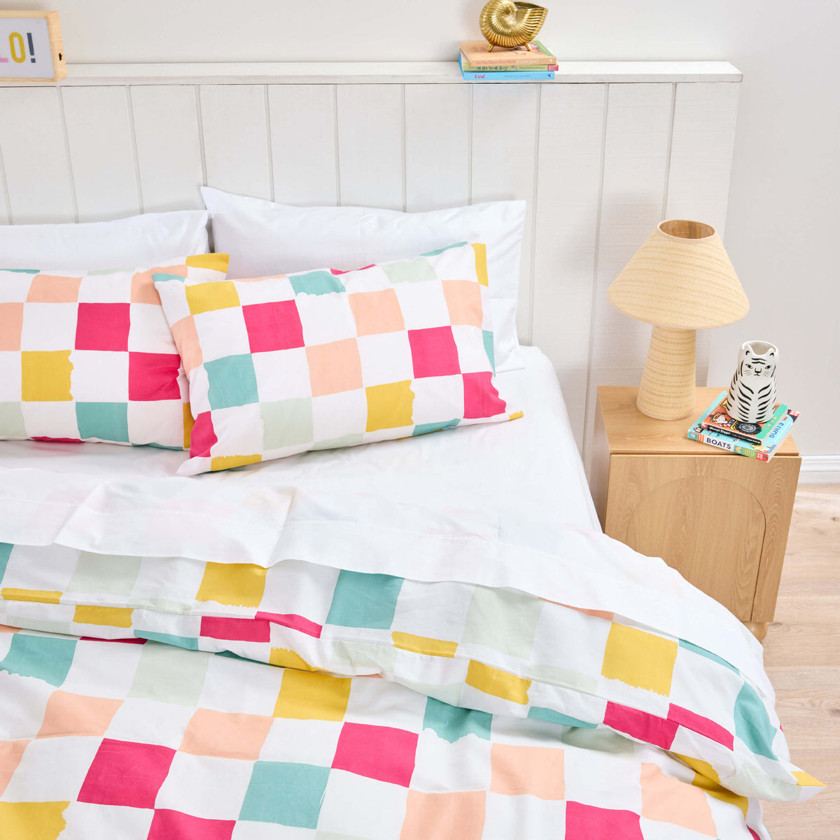 Large pink, mustard and green checks on a Twill & Co kids duvet set beside a wooden lamp