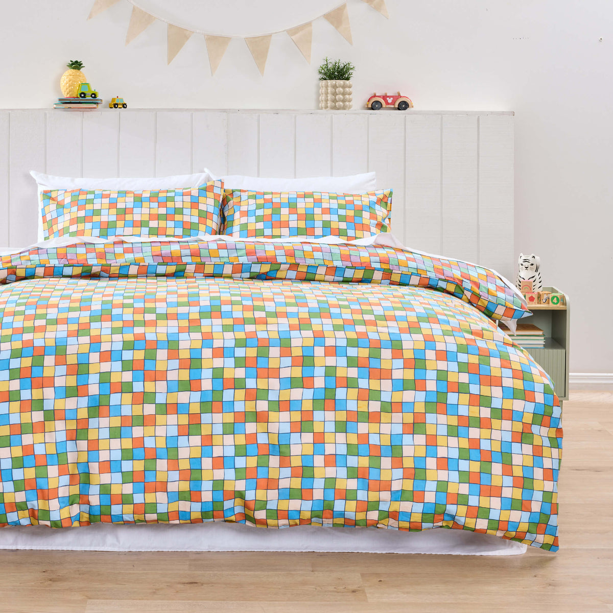 Twill & Co kids bedding covered in small multicoloured checks beneath triangular bunting