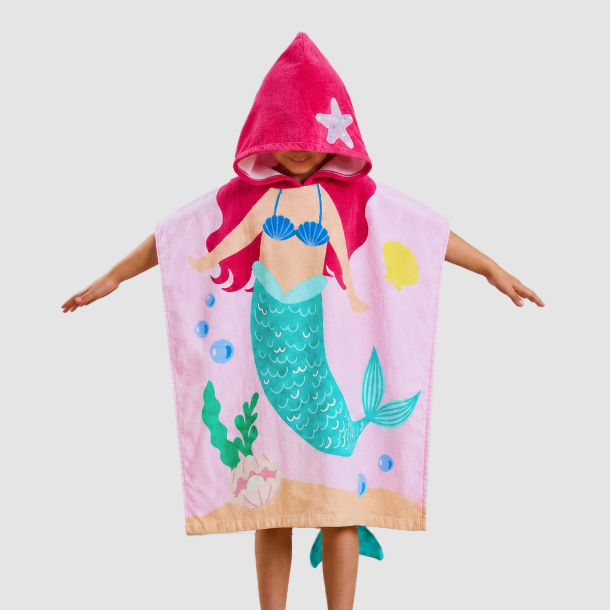 Child holding out a pink Twill & Co mermaid hooded towel with a turquoise tail illustration