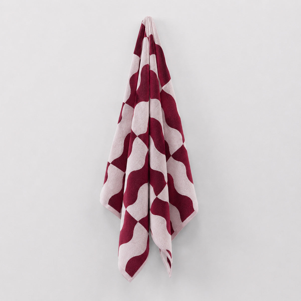 Twill & Co Squiggle Rumba Red beach towel hanging with its red and pale pink waves visible