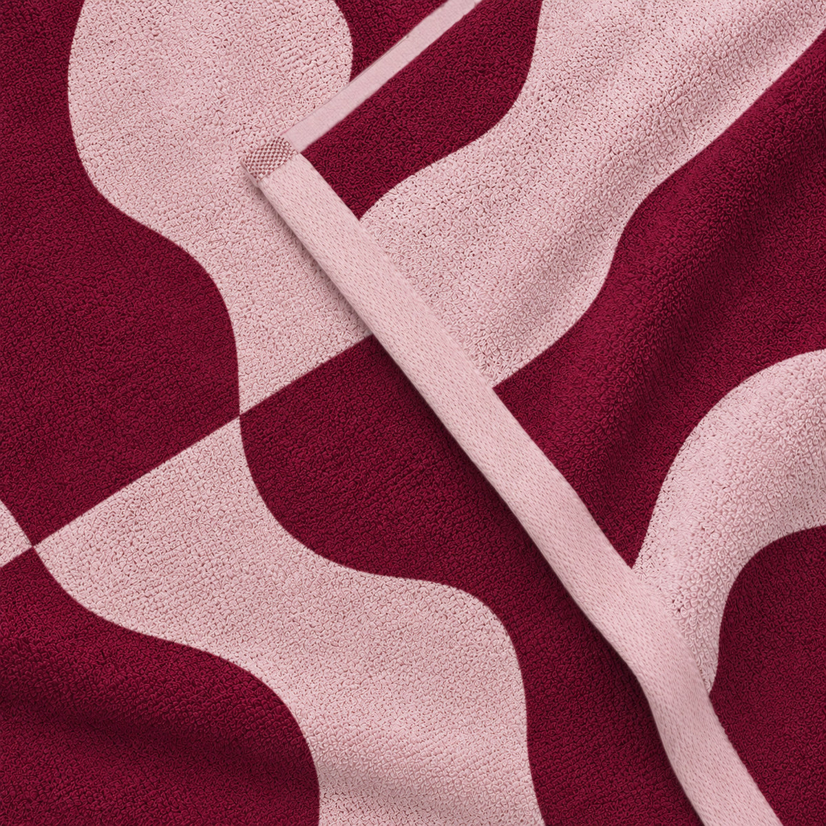 Folded corner showing the burgundy and pink wave pattern of a Twill & Co Squiggle towel