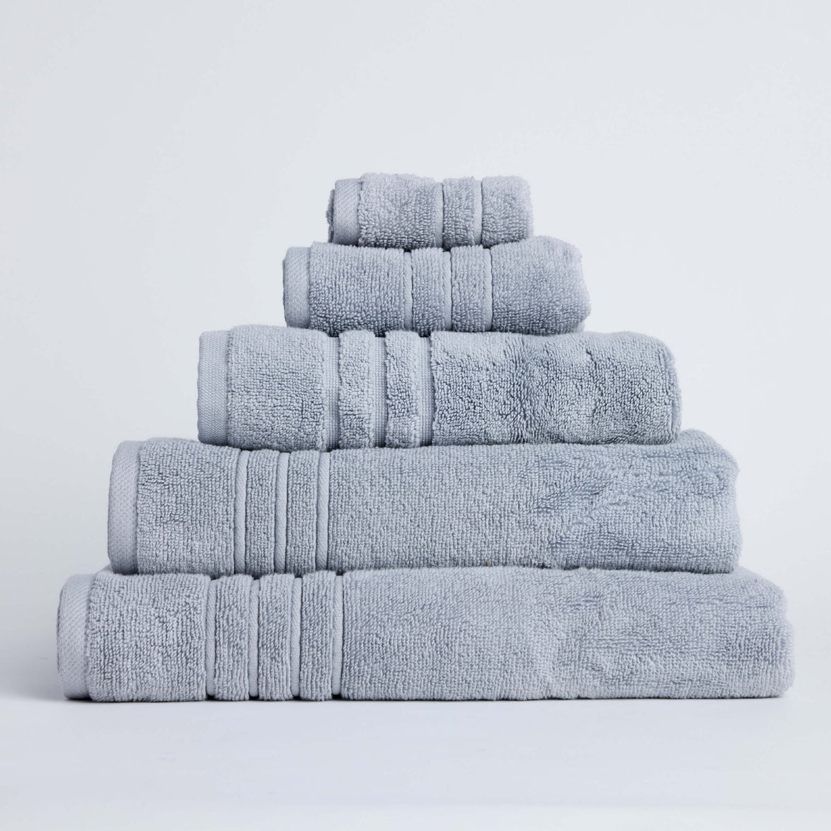 Stacked pale grey Twill & Co Sora towels with matching woven border stripes