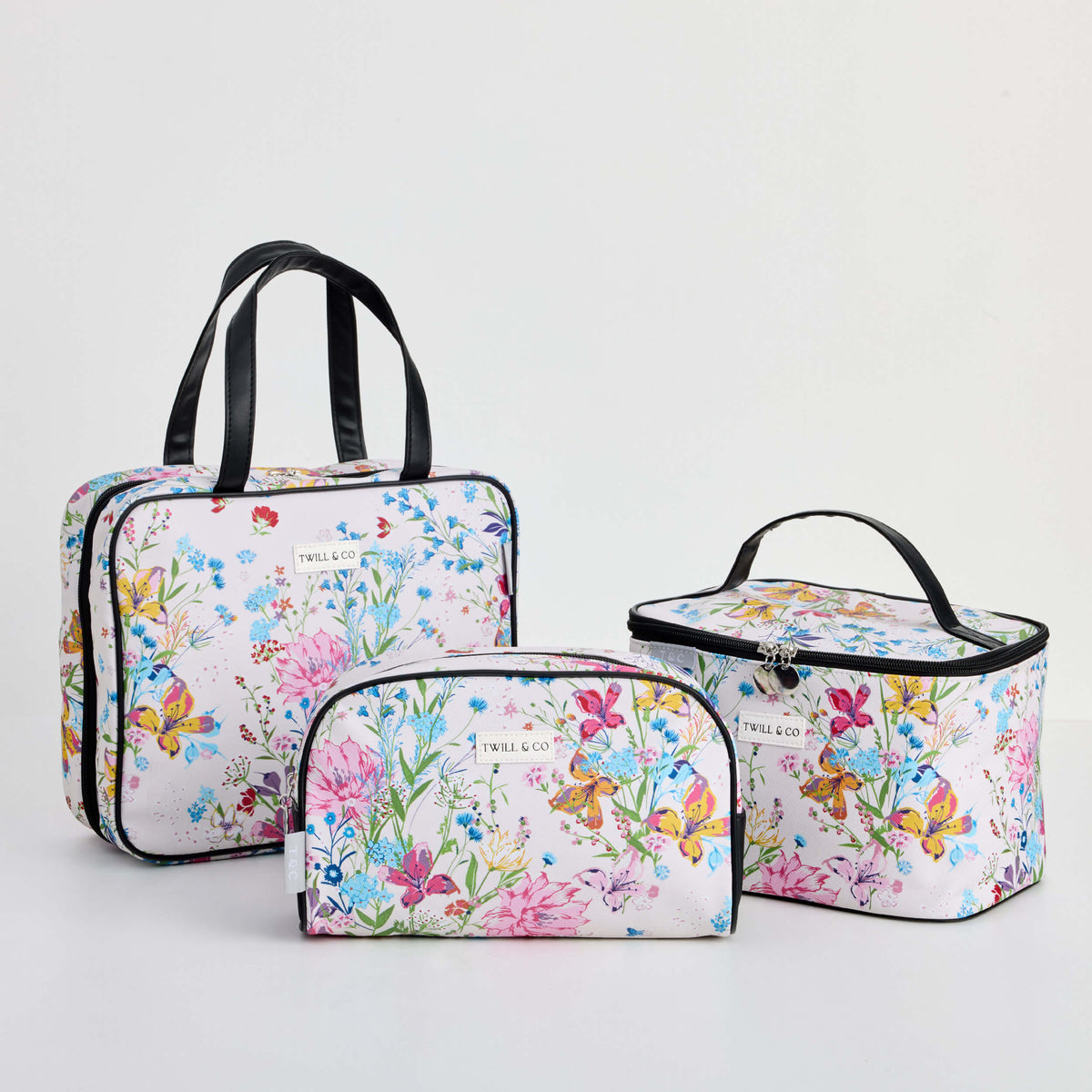 Three Twill & Co Liberty Natural toiletry bags with colourful flowers on a pale background
